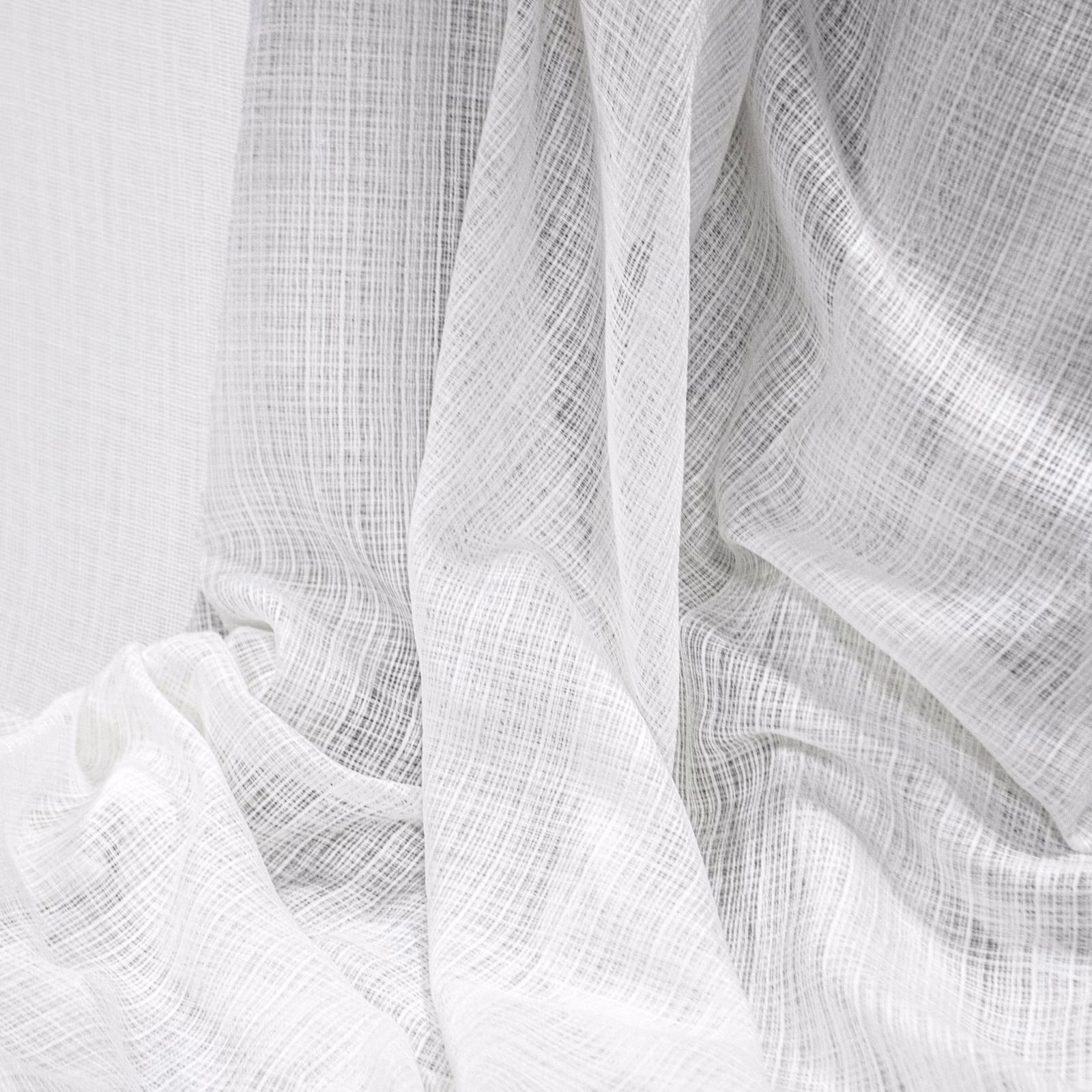 Soft white sheer fabric with fine crosshatch weave gathered into flowing folds