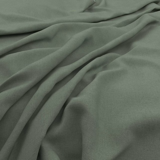 Muted sage green slubby fabric shown in fluid folds with a fine woven texture