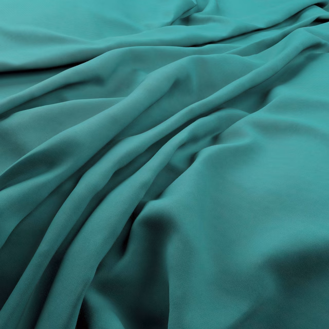Saturated teal fabric in fluid folds with a softly reflective, smooth surface