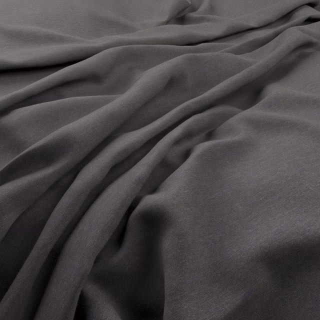 Slate-grey Solaire fabric draped in fluid folds with a fine, softly textured surface