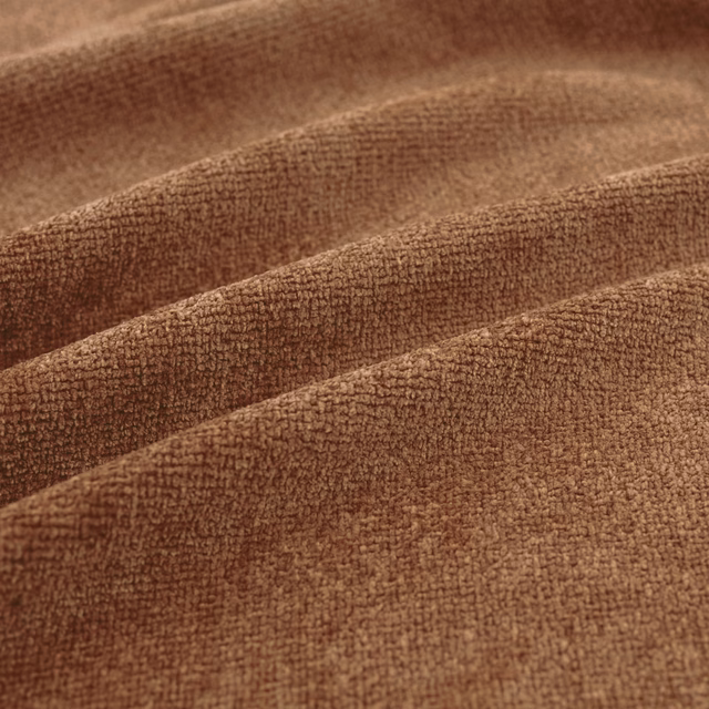 Warm rust-brown fabric with fine nubby texture arranged in broad, softly shaded folds