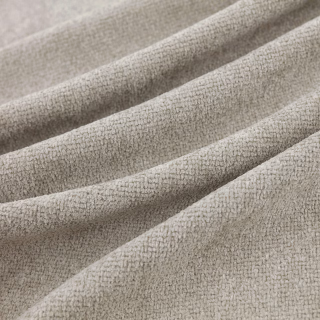 Pale silver-grey nubby fabric with a softly pebbled weave folded into broad tactile ridges