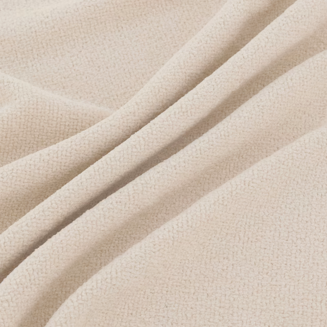 Warm vanilla cream fabric with fine pebbled texture arranged in soft flowing folds