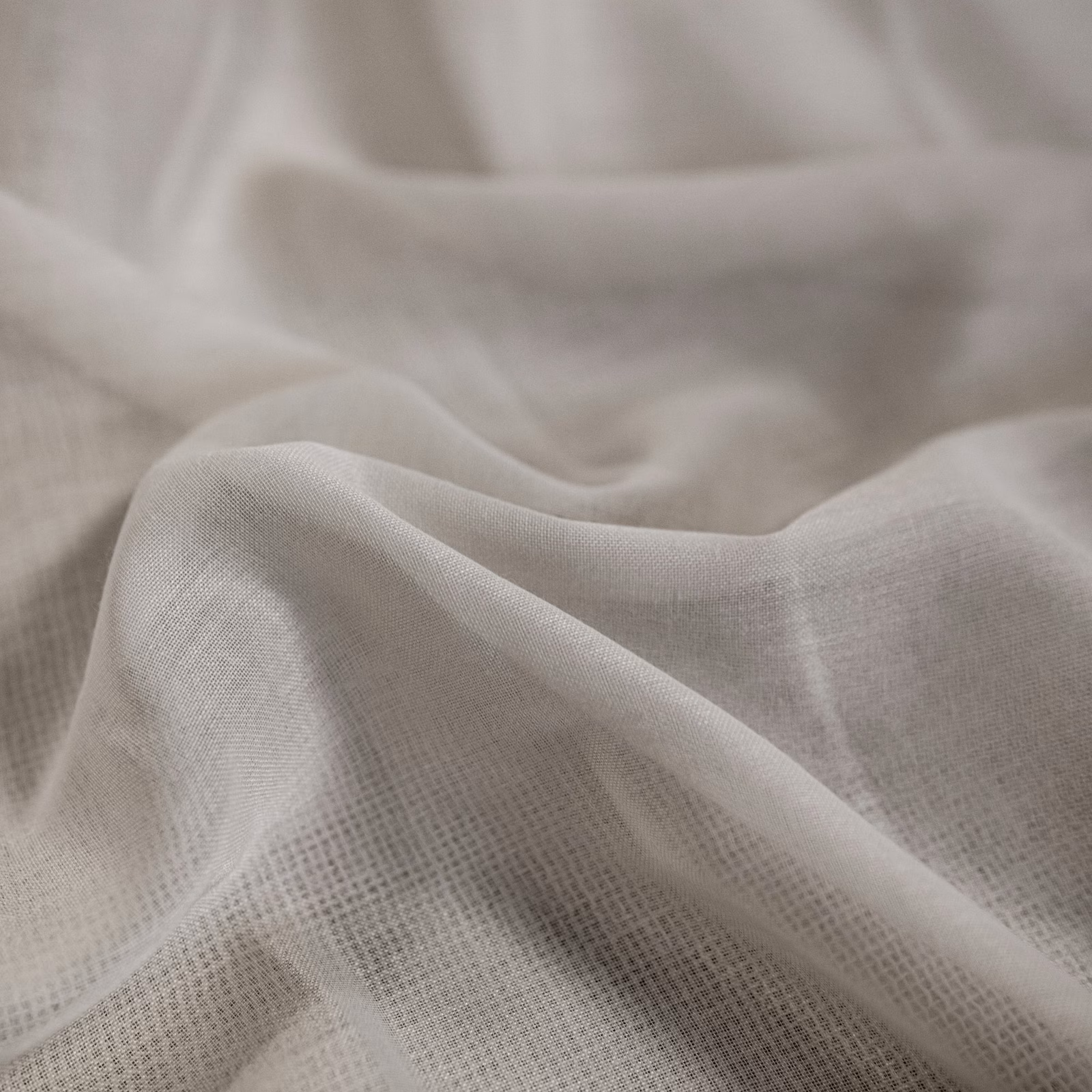 Soft ivory open-weave fabric gathered into lightly translucent flowing folds