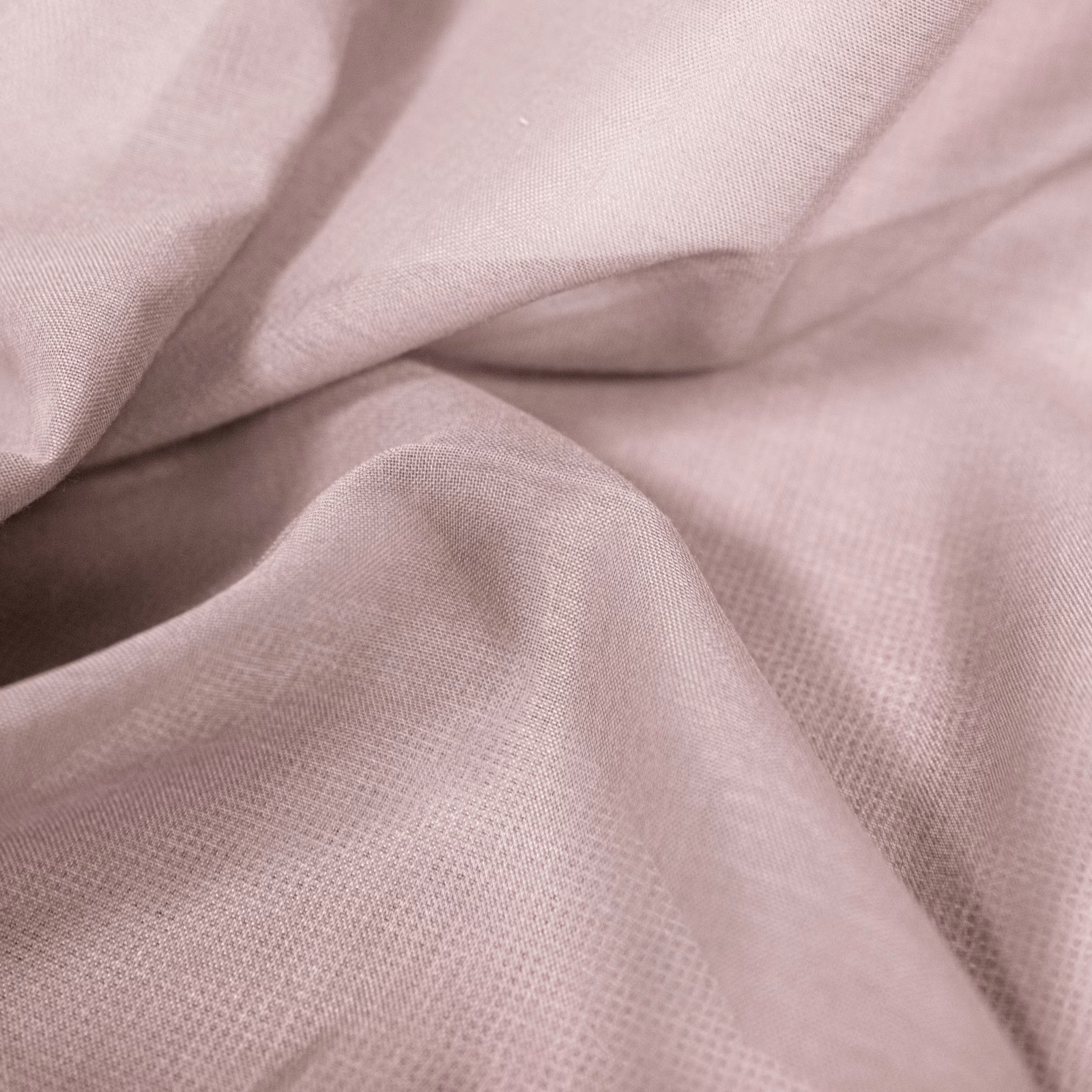 Close-up of dusty shell pink fabric with a fine plain weave and soft folded texture