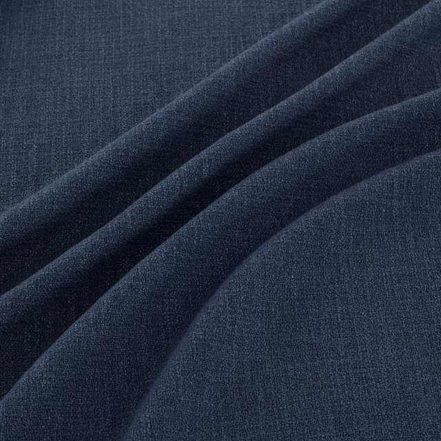 Deep indigo woven fabric with fine crosshatch texture falling into broad folds