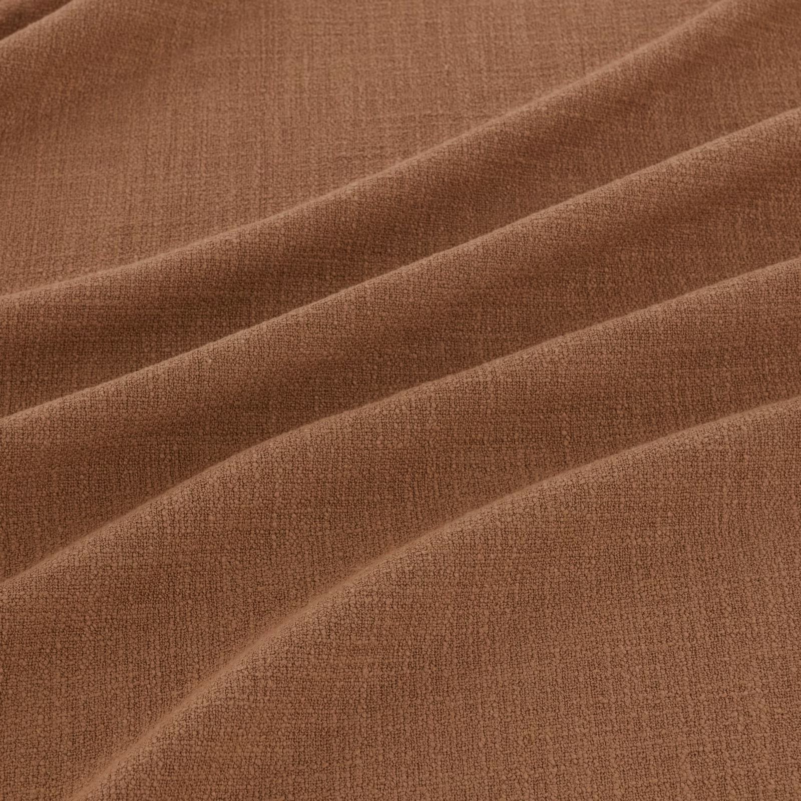 Warm kiln-brown woven fabric with fine texture arranged in broad diagonal folds