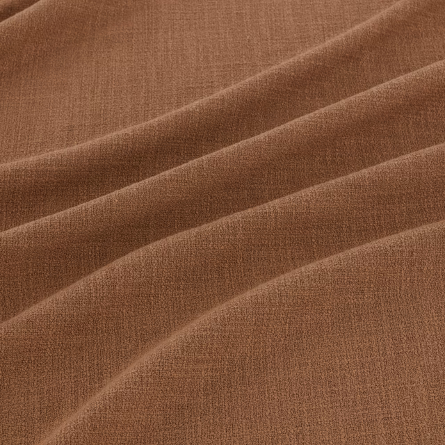 Warm kiln-brown woven fabric with fine texture arranged in broad diagonal folds