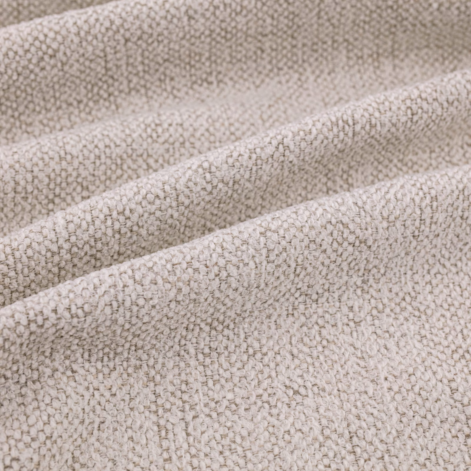 Warm ecru woven fabric with irregular raised pebble texture and soft folded ridges