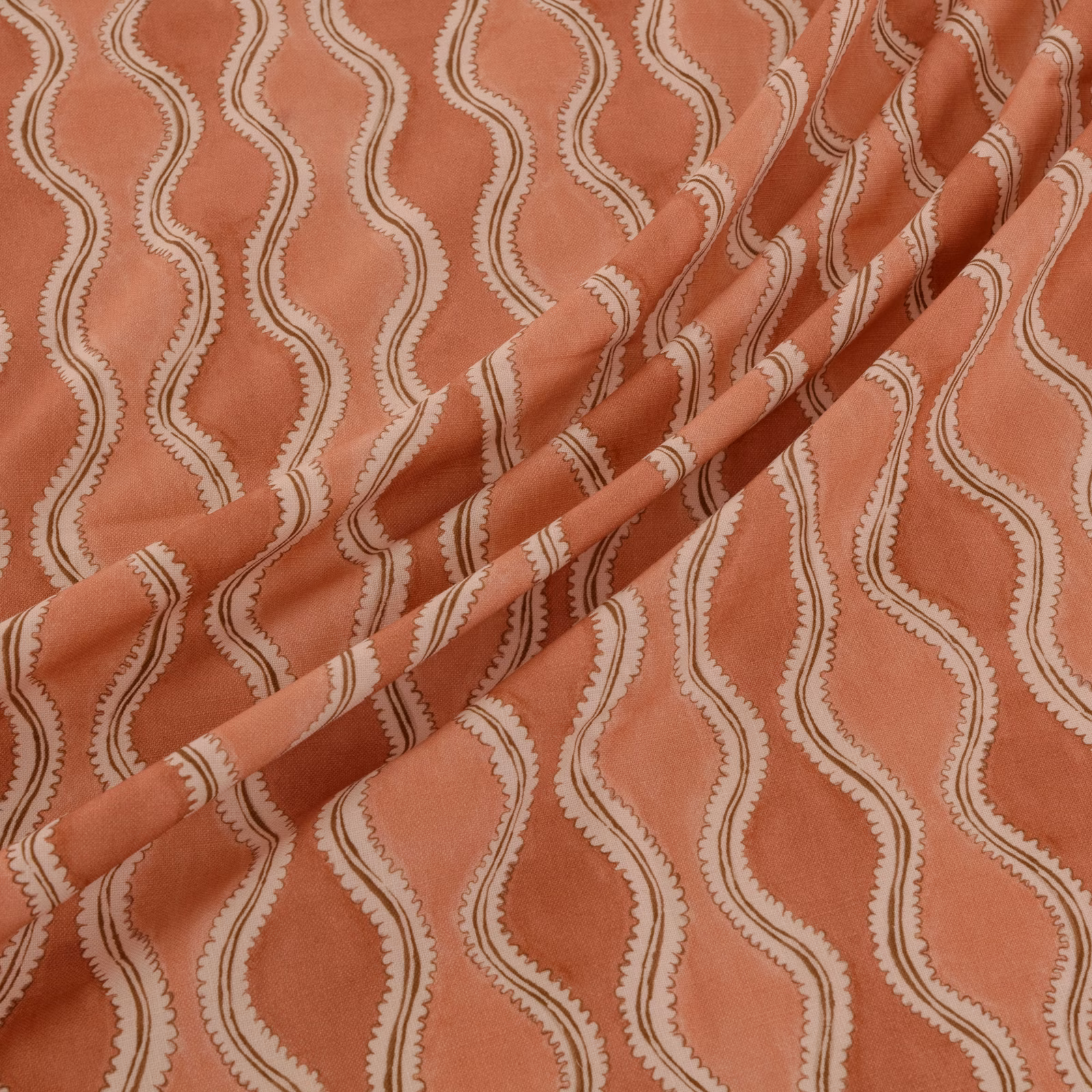Muted coral terracotta fabric with cream serpentine stripes and softly textured surface