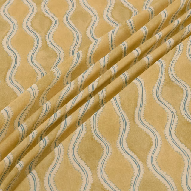 Warm golden fabric with cream panels and blue-grey undulating lines in folded drape