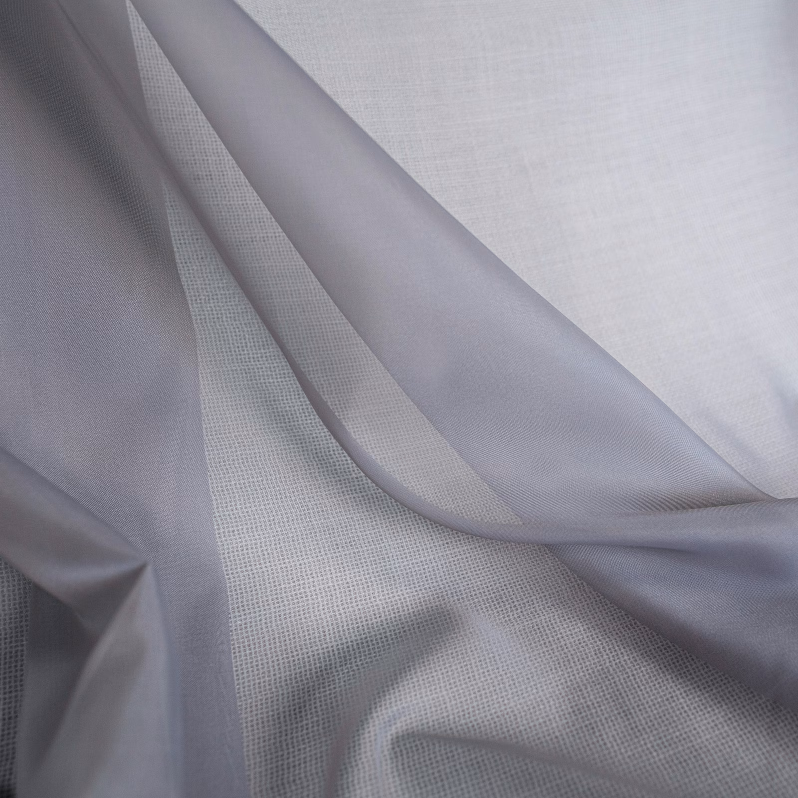 Pale cool-lilac fabric in fluid folds over a fine open grid weave