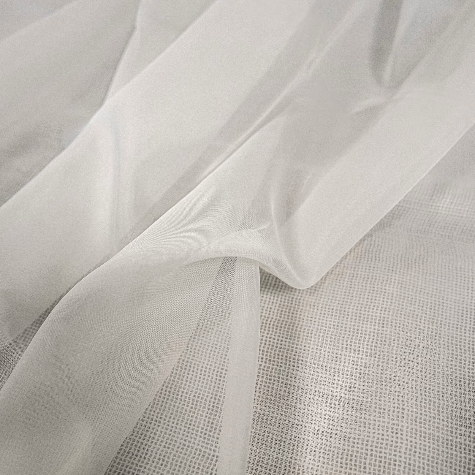 Translucent ivory-white sheer fabric draped in soft folds over a fine grid weave