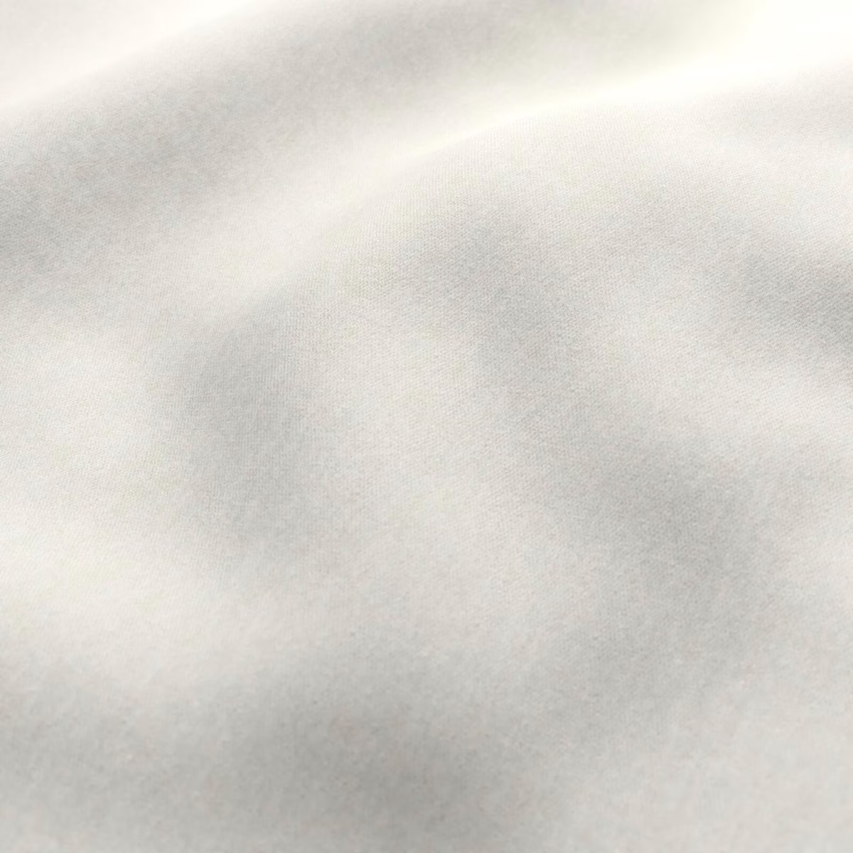 Pale porcelain cream fabric with a soft, cloudy tonal woven surface