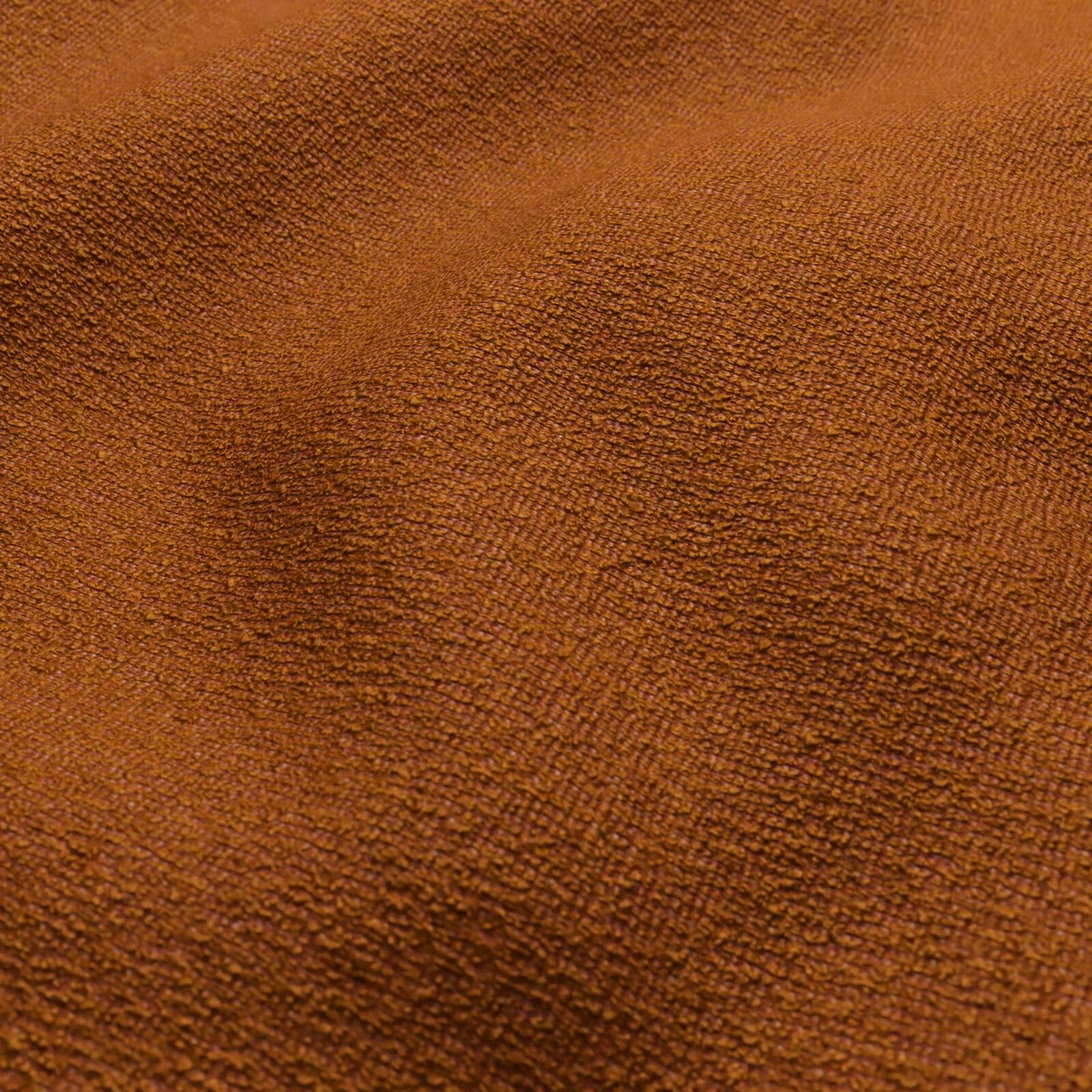 Close-up of warm pumpkin-orange fabric with dense, rippled brown texture