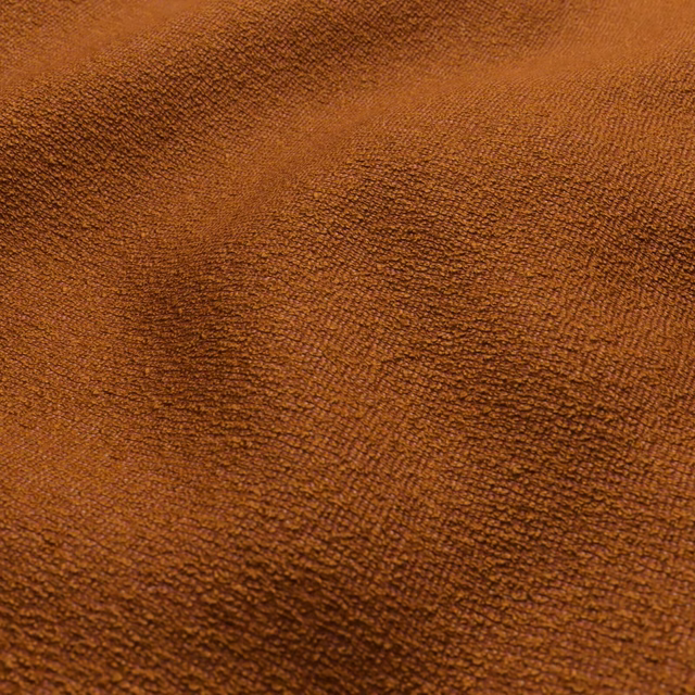 Close-up of warm pumpkin-orange fabric with dense, rippled brown texture