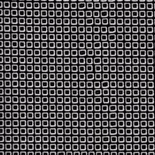 Black woven fabric with tightly repeated chalk outlined squares in a grid