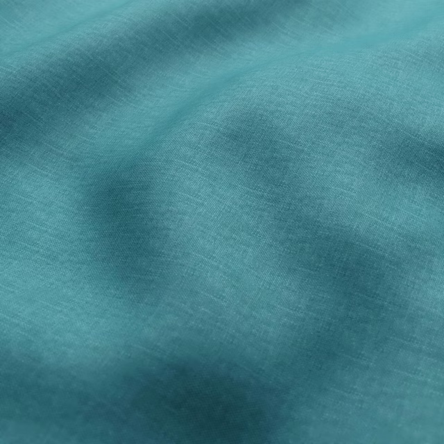 Close-up of softly mottled turquoise textile with a fine woven texture