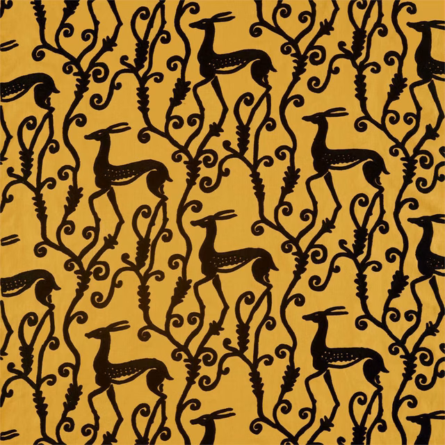 Ochre-gold fabric with black deer, curling vines and a dense botanical repeat