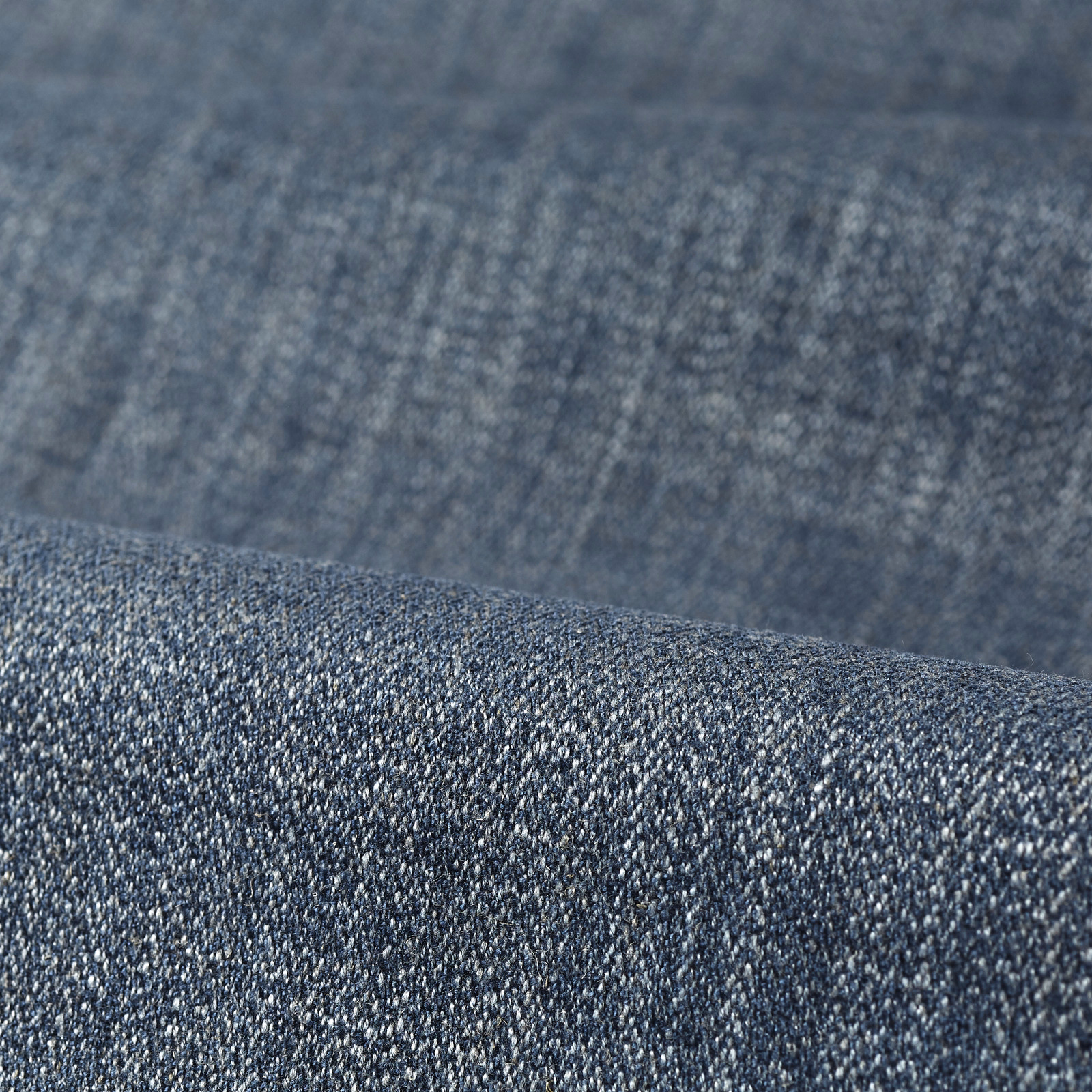 Close-up of muted denim-blue fabric with dense, salt-and-pepper woven texture