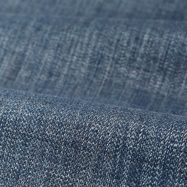 Close-up of muted denim-blue fabric with dense, salt-and-pepper woven texture