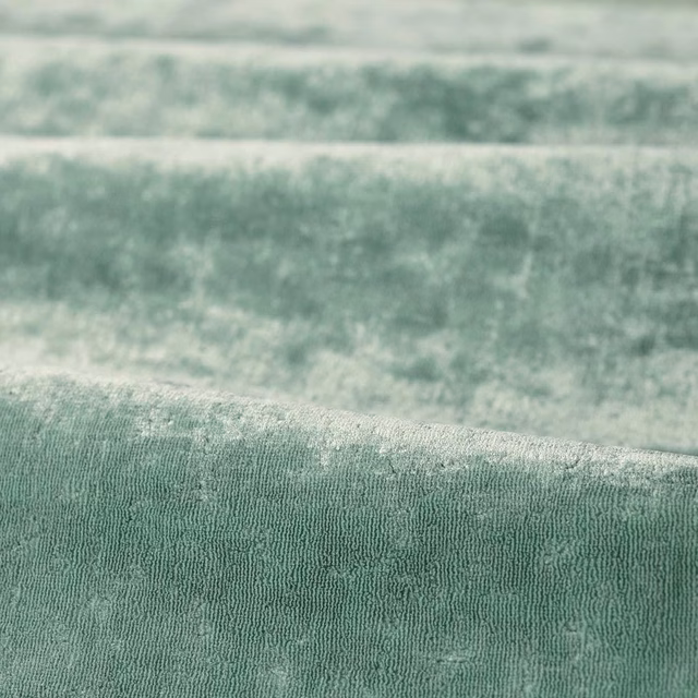 Soft eau de nil green fabric with fine irregular woven ridges and tonal shading
