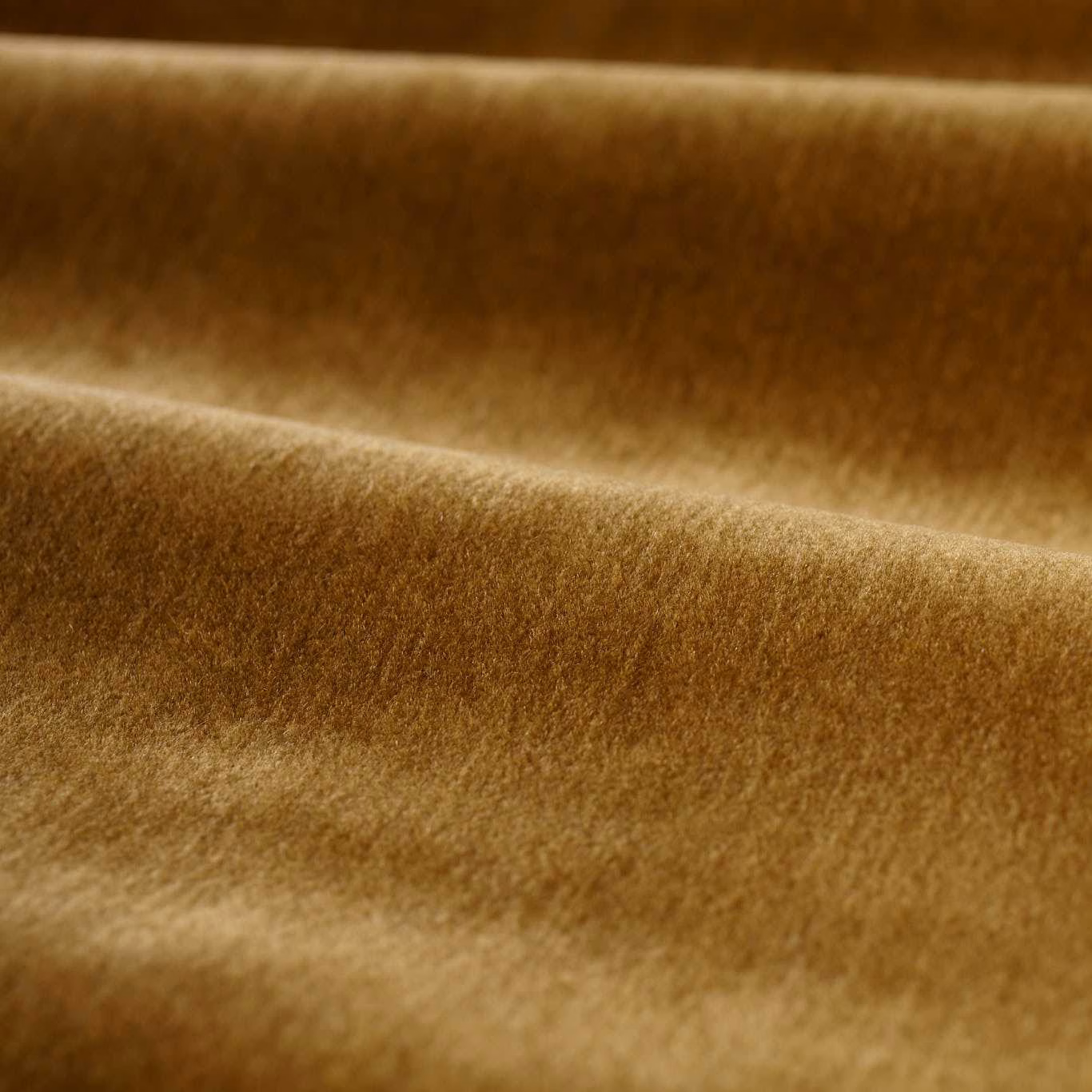 Close-up of warm amber-brown plush pile showing darker folds and golden highlights