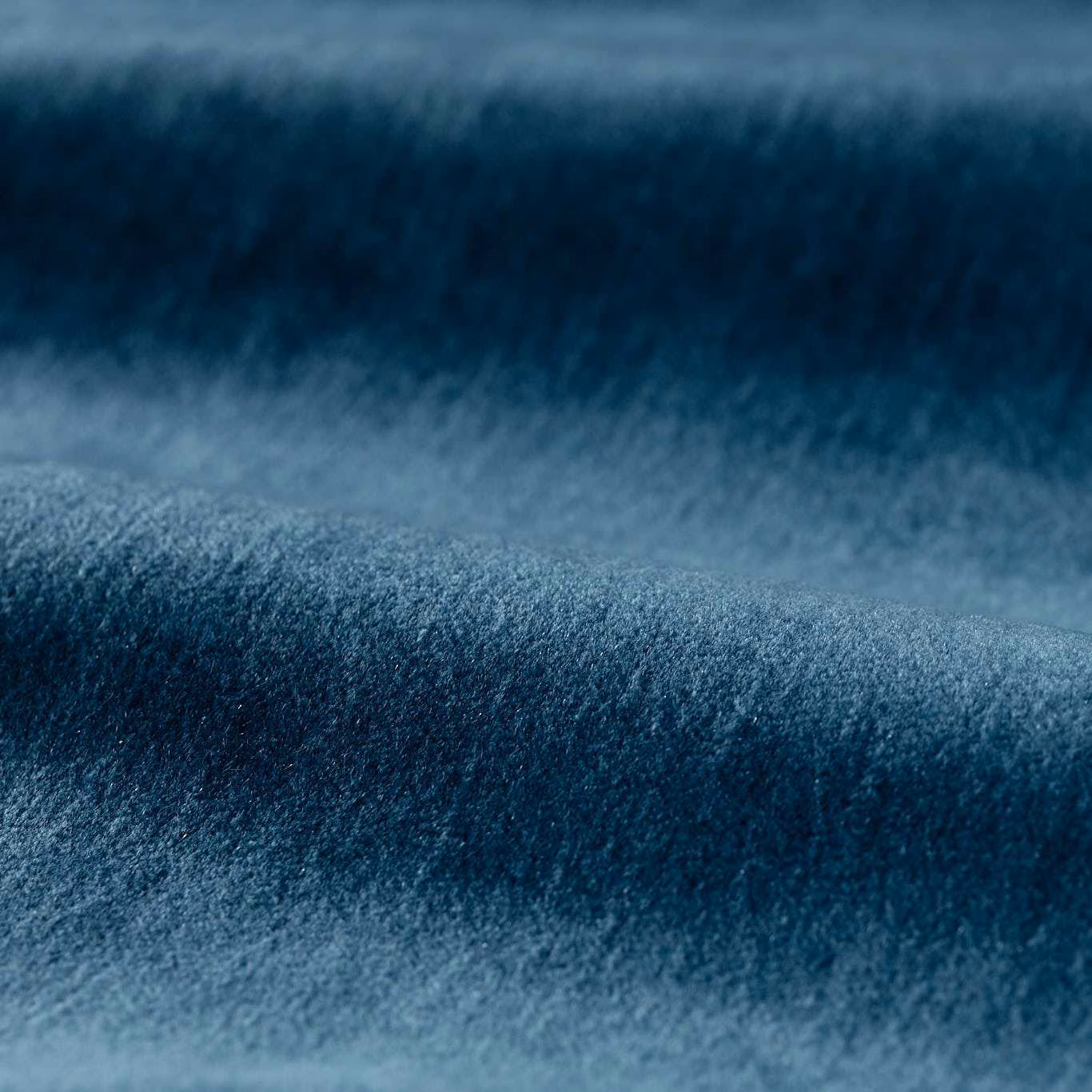Deep mazarine blue plush pile showing soft blue-grey highlights across a rolled fabric swatch