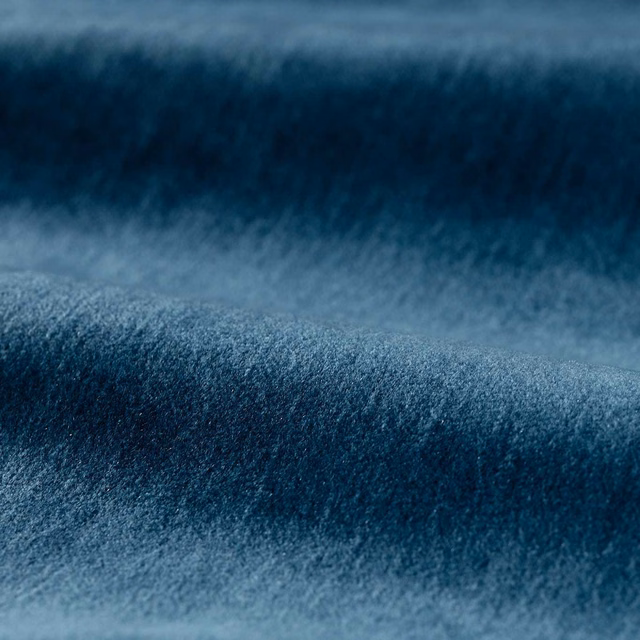 Deep mazarine blue plush pile showing soft blue-grey highlights across a rolled fabric swatch