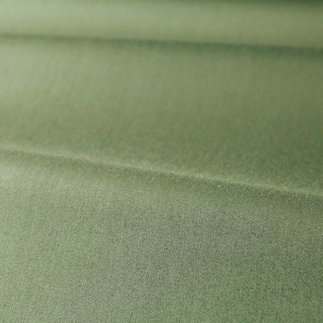 Close-up of muted sage green plain fabric with a soft satin sheen and fine texture