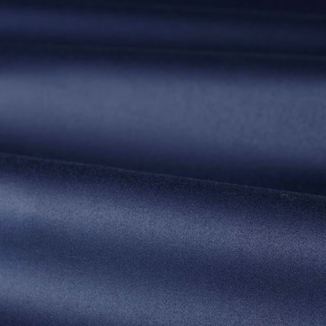 Folded deep indigo blue satin fabric showing smooth sheen and shadowed tonal bands
