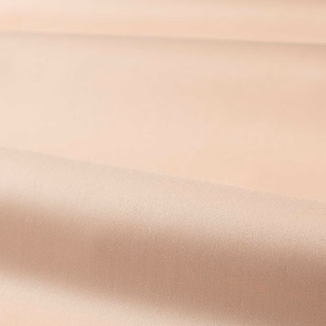 Folded plain Rose Quartz fabric showing a smooth blush-beige satin sheen