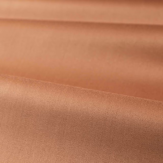 Warm copper-taupe satin fabric folded to show smooth lustrous tonal shading