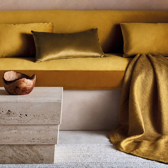 Burnished ochre-gold textile with subtle weave draped beside matching upholstered seating