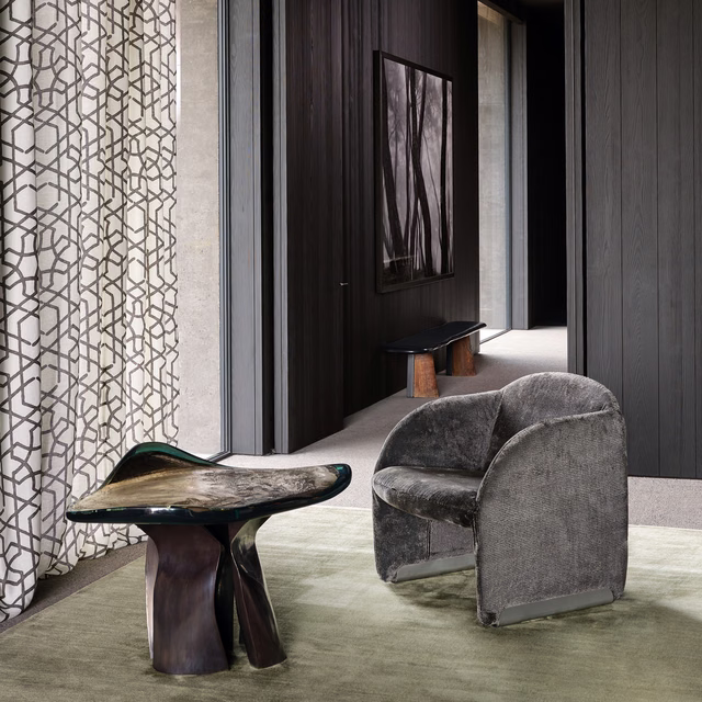 Ivory curtain with charcoal interlocking lattice pattern beside a grey upholstered chair