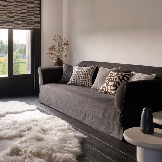 Black, cream and taupe abstract patterned cushion on a dark charcoal sofa