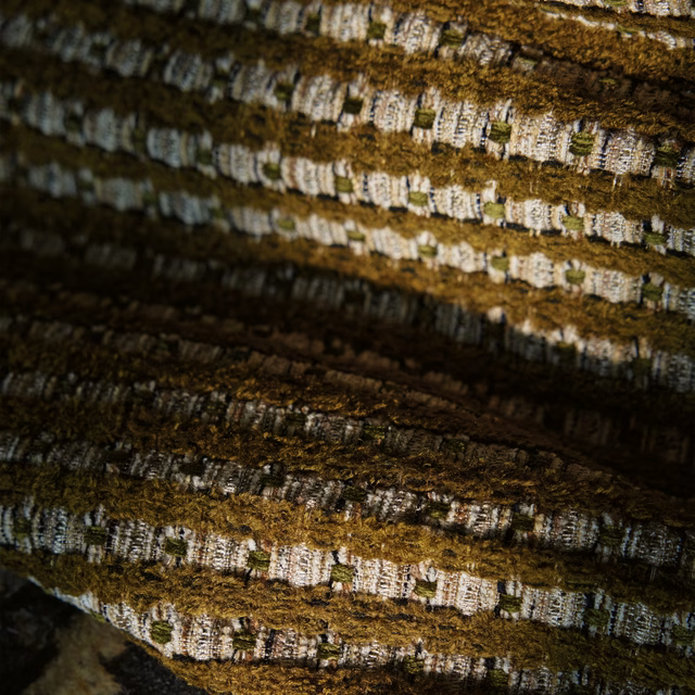 Close-up of deep olive khaki fabric with raised ridges and pale woven flecks