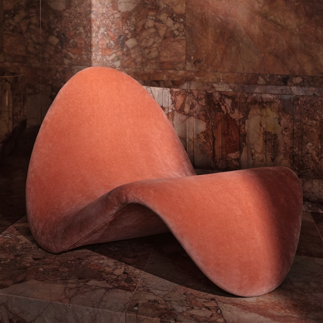 Watermelon coral velvet with soft sheen across a sculptural curved chair