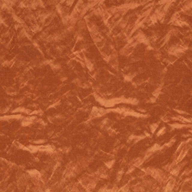 Close-up of warm cognac fabric with crumpled, marbled pile and rust highlights