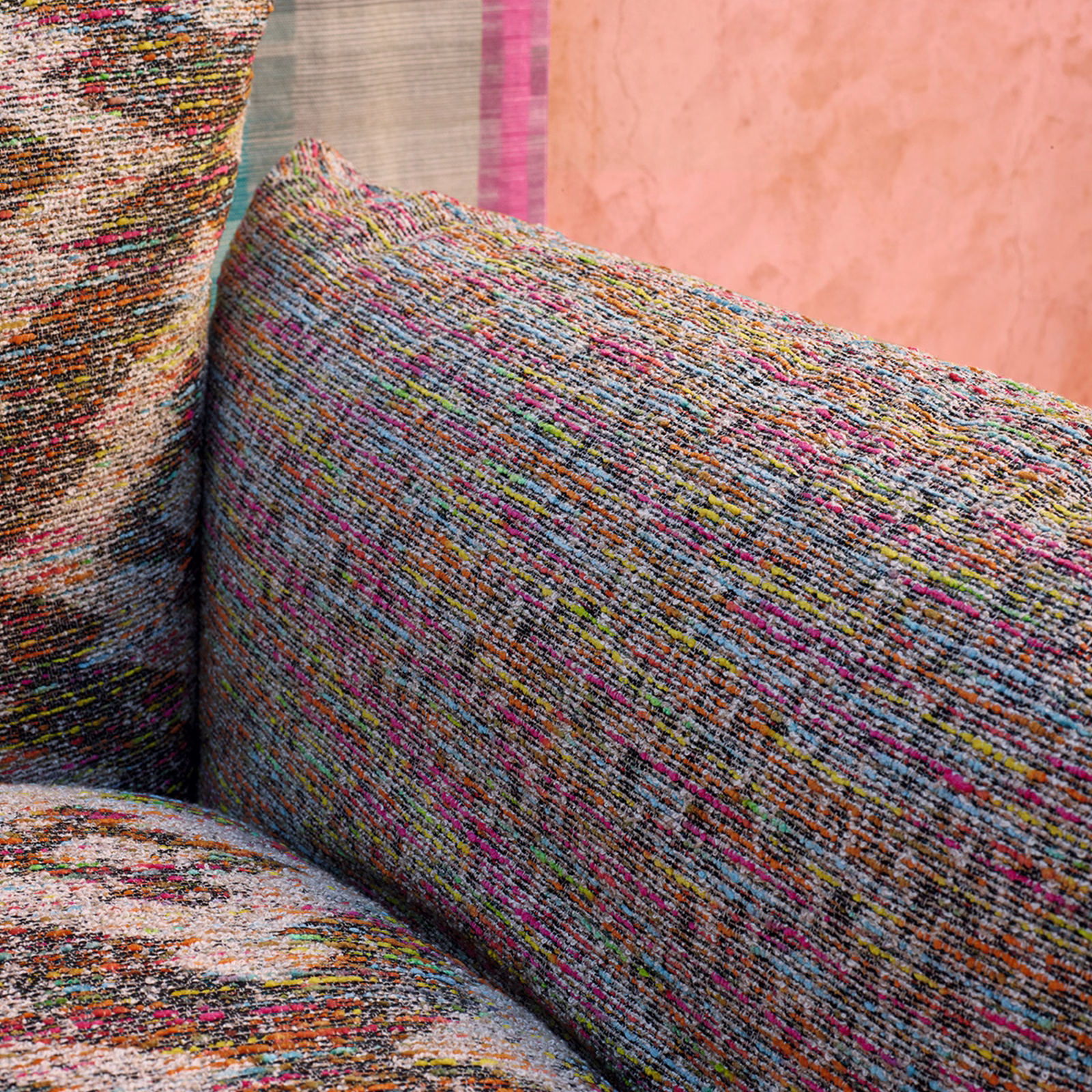 Dense rainbow-flecked weave in pink, teal, ochre and charcoal on a cushion