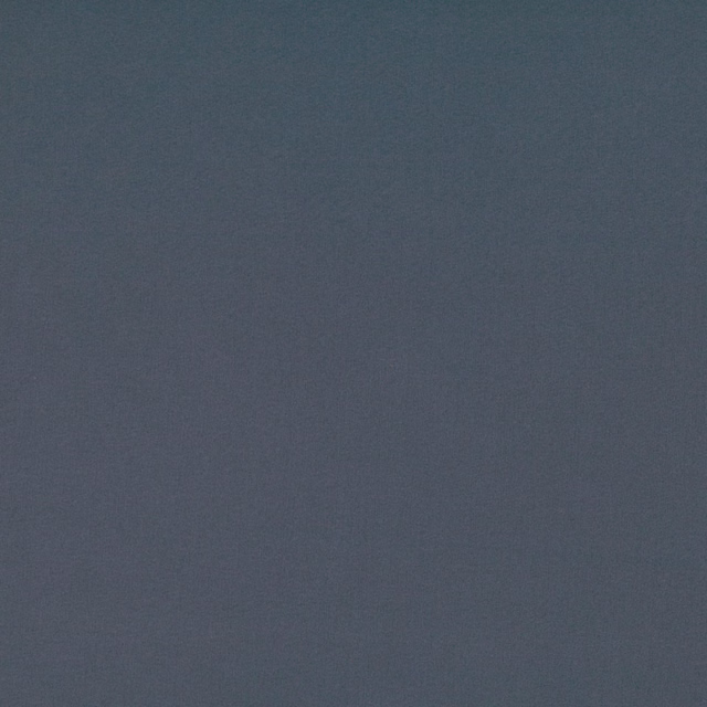 Close view of muted carbon blue fabric with a fine, subtly textured weave