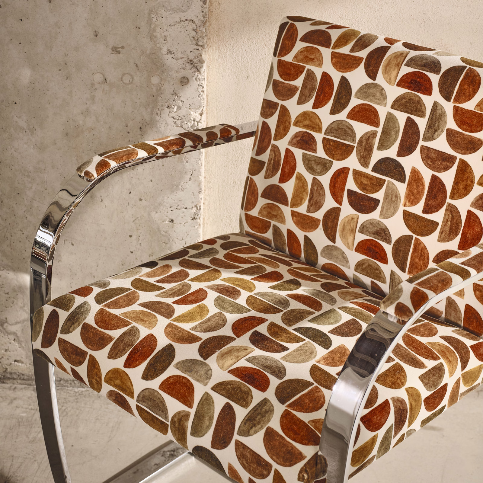 Russet, tan and olive pebble motifs on ivory upholstery covering a modern armchair