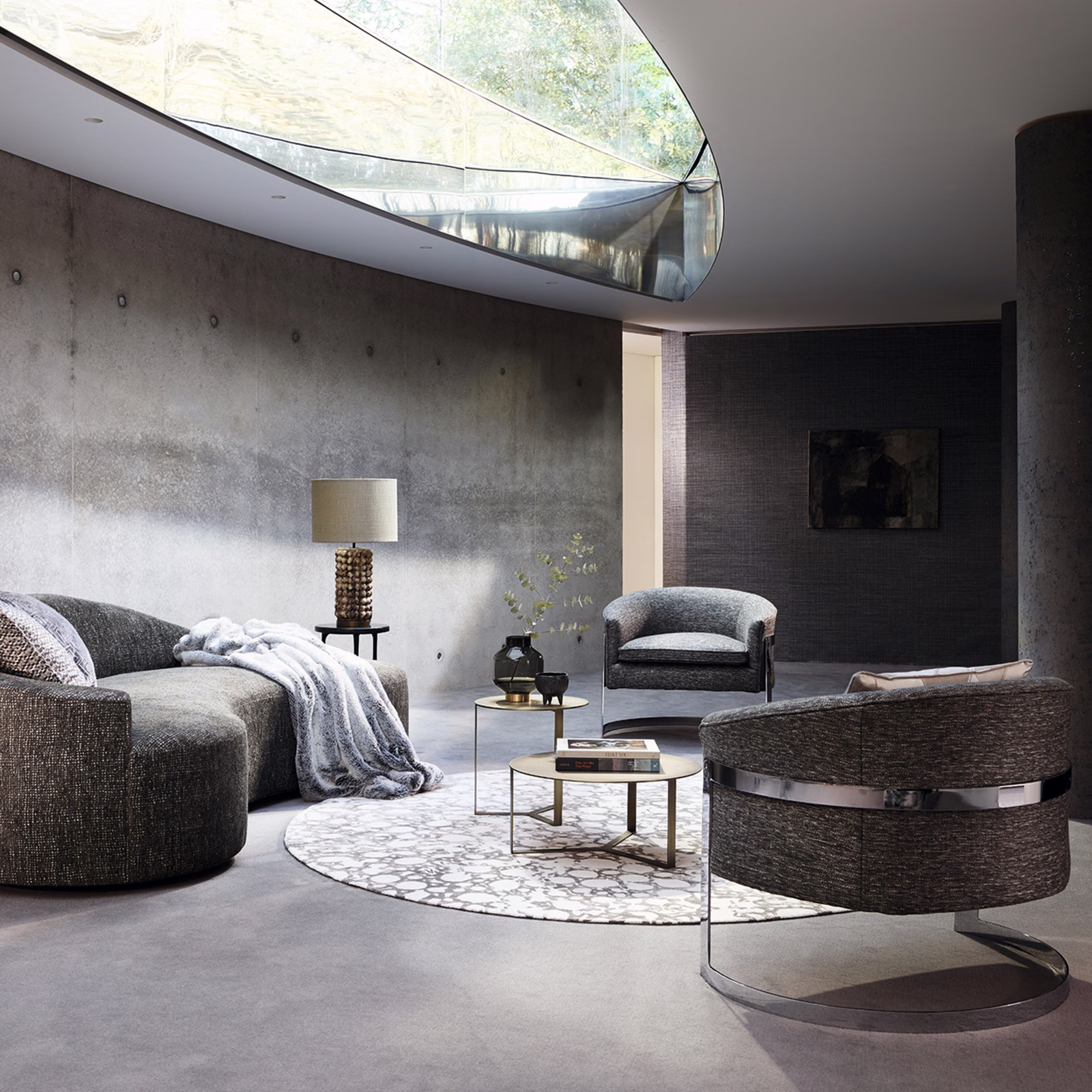 Cool mineral-grey textured upholstery on curved sofa and barrel chair in soft light