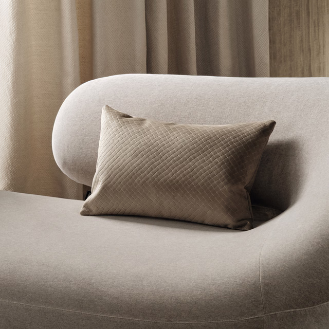Pale greige textured upholstery on a curved chair beside a taupe diamond-quilted cushion