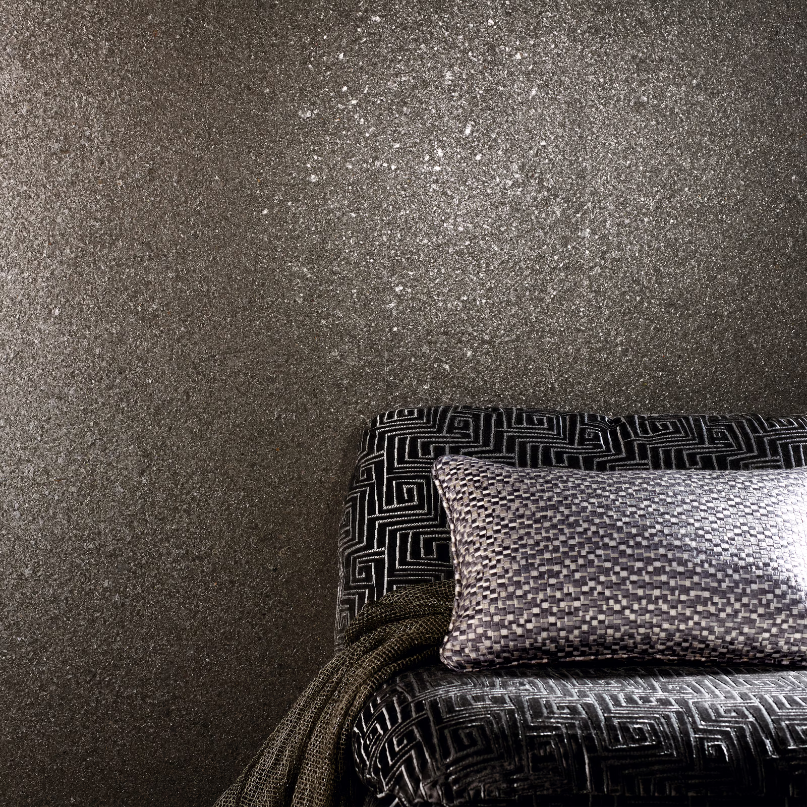 Dark taupe-grey mineral wallcovering with pale flecks and a granular patina texture