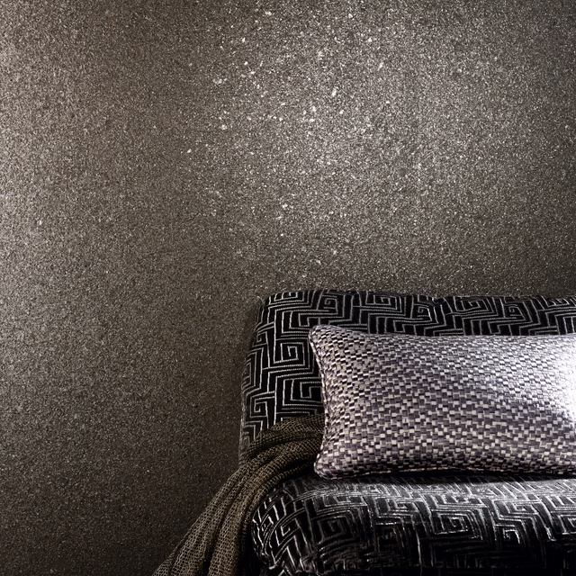 Dark taupe-grey mineral wallcovering with pale flecks and a granular patina texture