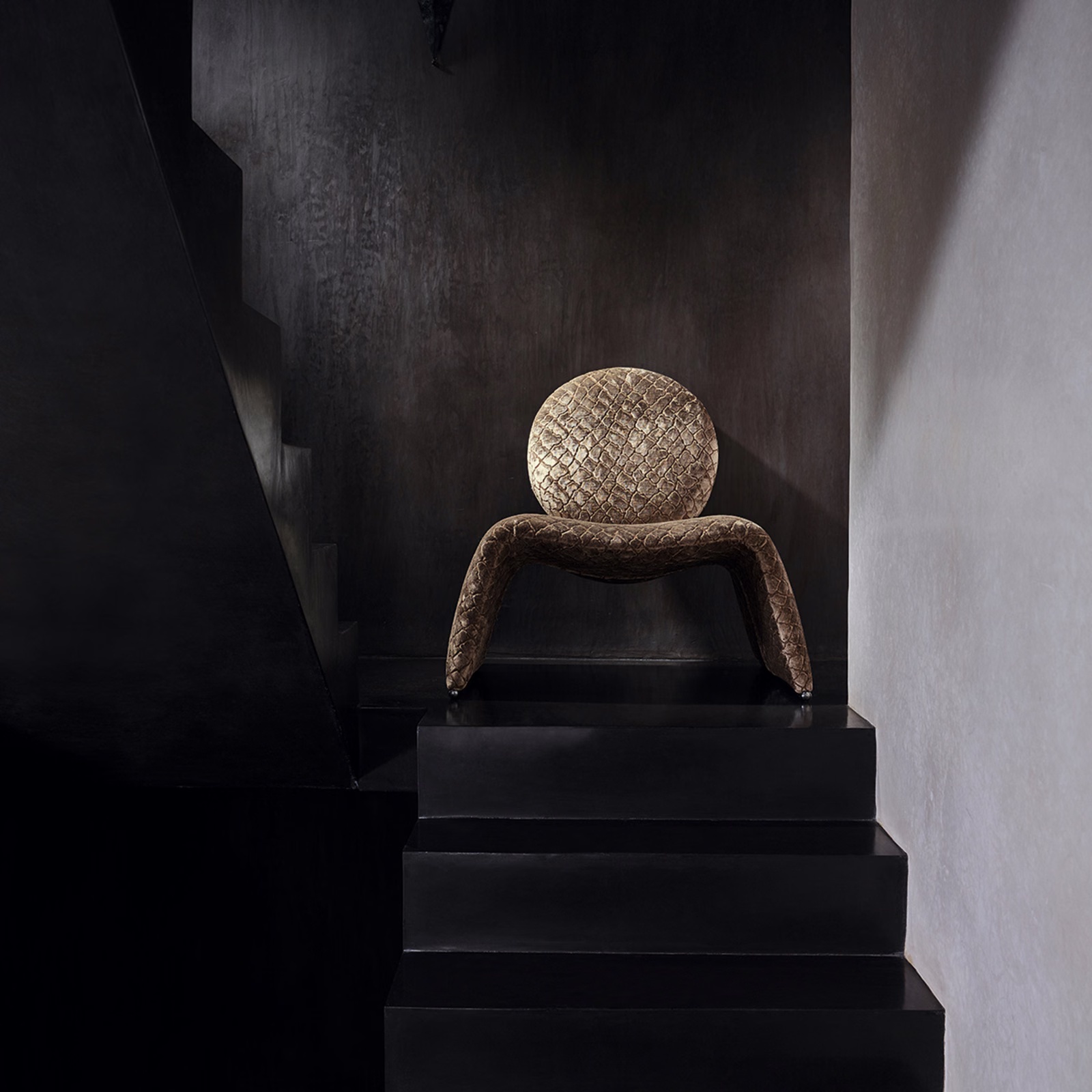 Warm tobacco-brown scaled upholstery with bronzed highlights on a sculptural chair