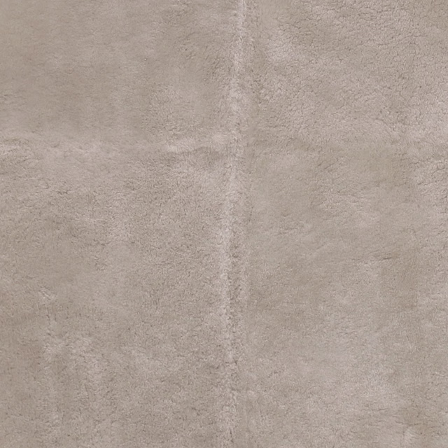 Warm buff-beige sheepskin-textured fabric with a softly mottled short pile