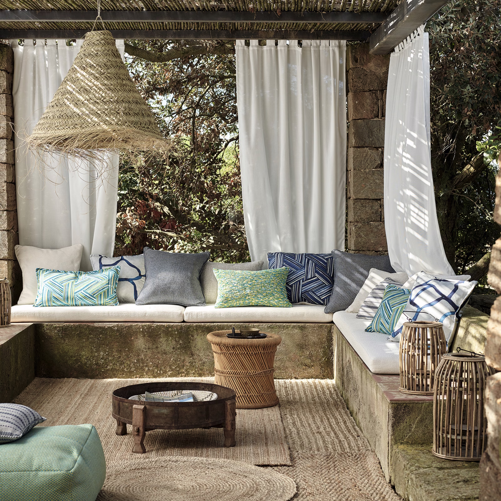 Muted ocean-blue and green patterned cushion fabric in a sunlit outdoor seating area