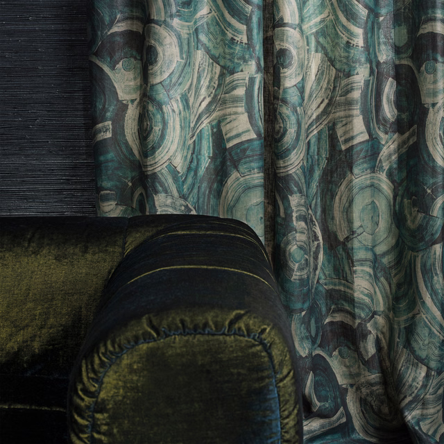 Deep teal abstract swirl fabric falling in folds beside dark olive seating
